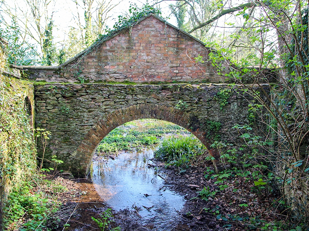 Historic boathouse and stone arch crossing water at Fyne Court